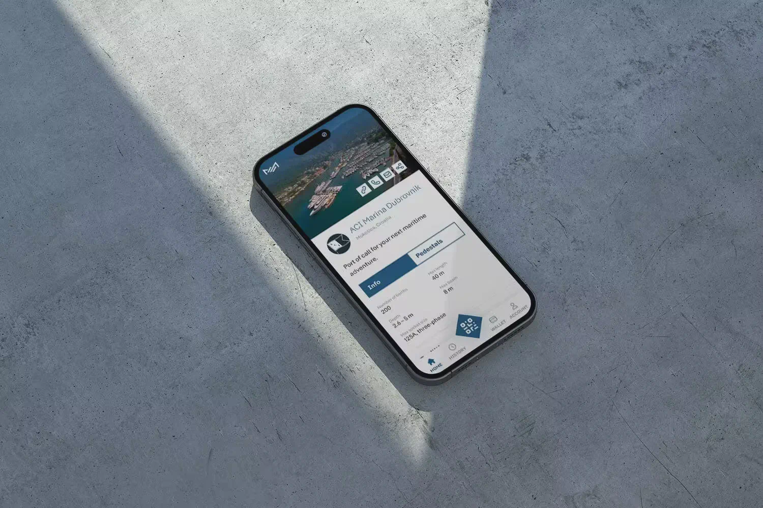 An iPhone lying on a grey concrete surface shows the Marex.es marina management app interface with business metrics.
