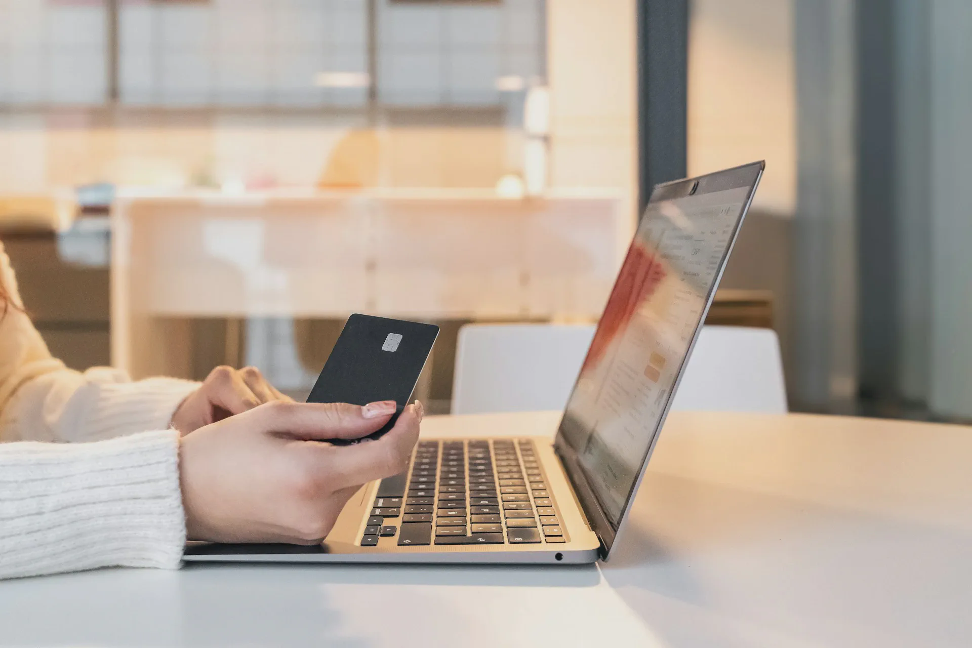 Person shopping online in front of laptop, holding credit card